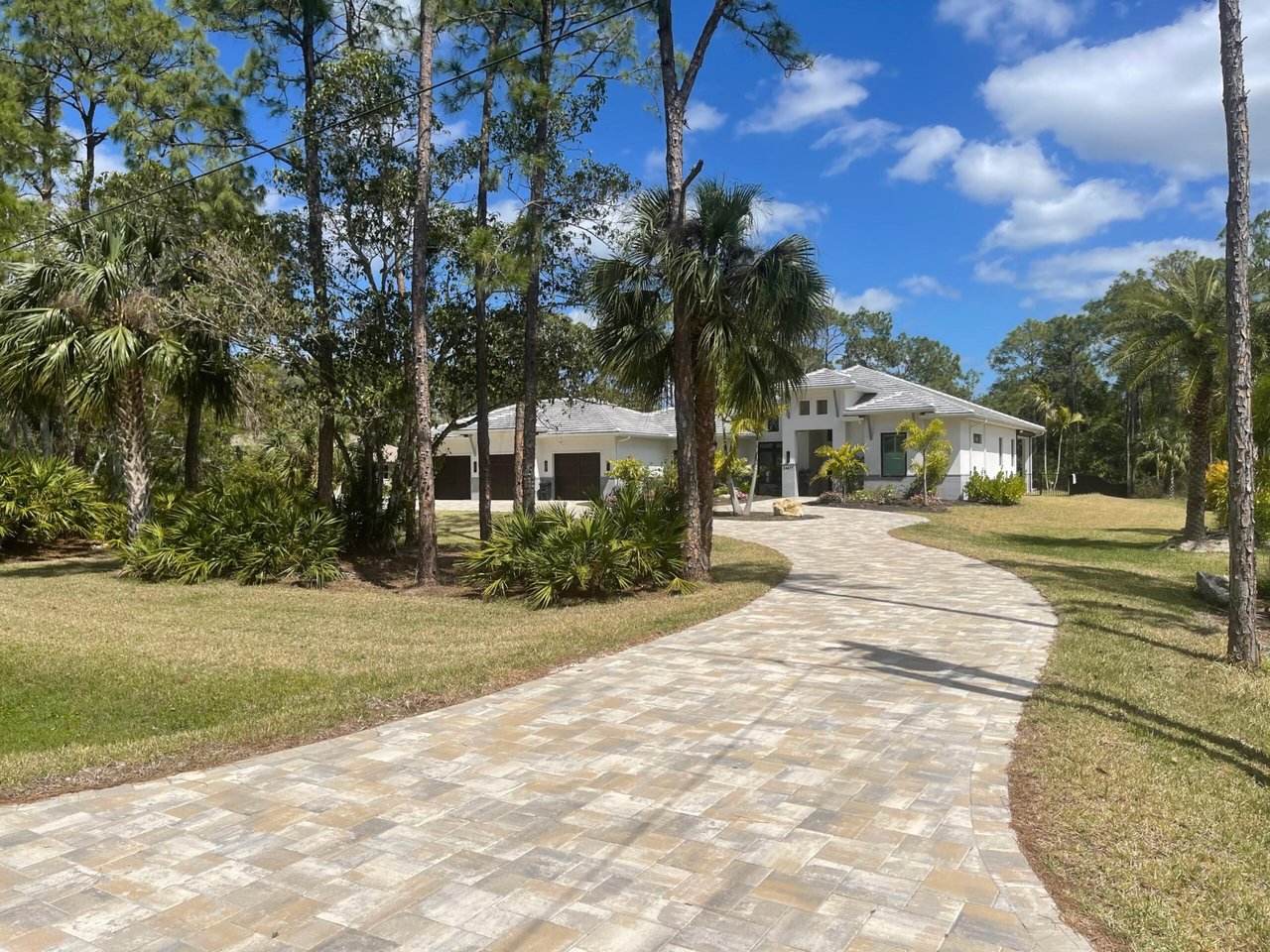 Long curved paver driveway leading to a Southwest Florida estate